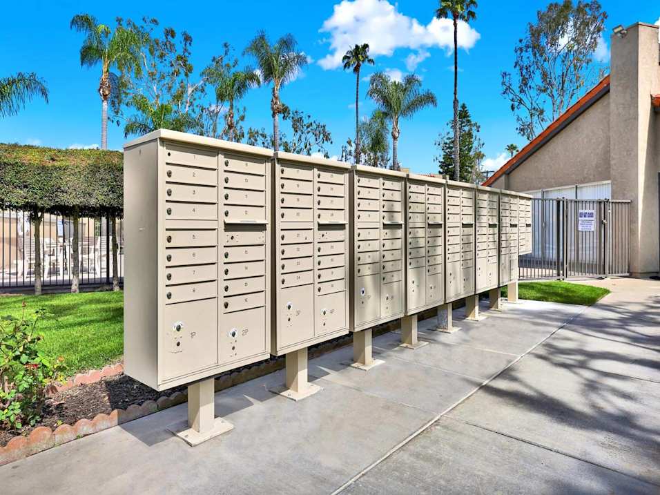 A row of mailboxes are lined up on a sidewalk.