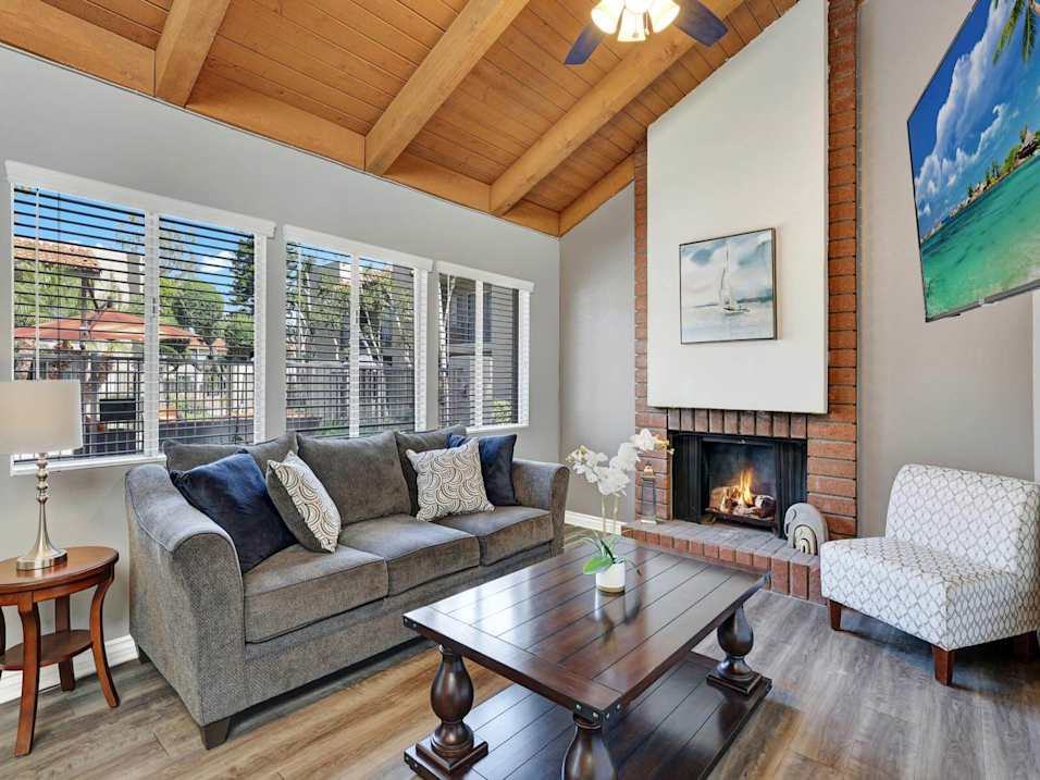 A living room with a grey couch and a fireplace.