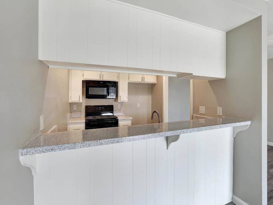 A kitchen with white cabinets and a granite countertop.