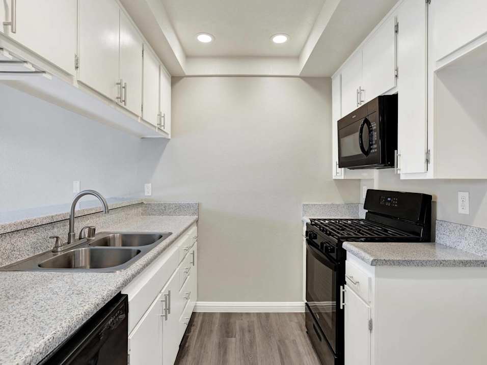 A kitchen with black appliances and white cabinets.