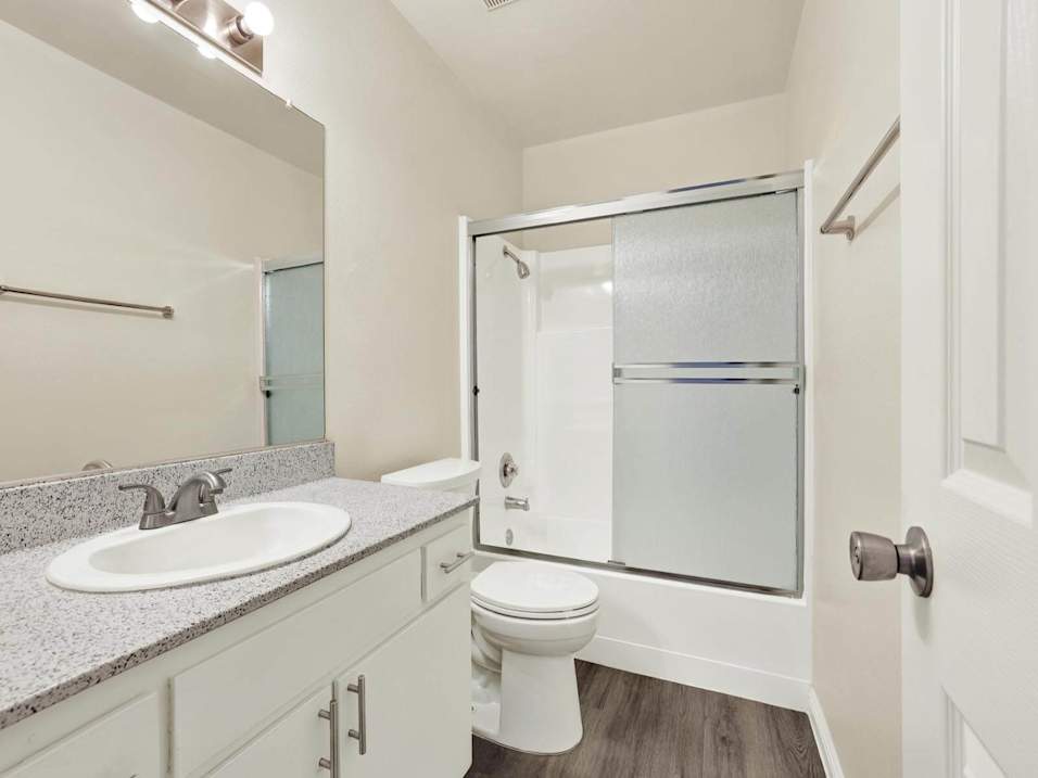 A white bathroom with a toilet, sink, and shower.