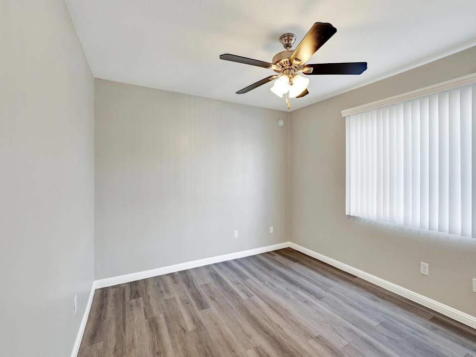 A room with a ceiling fan and wooden flooring.