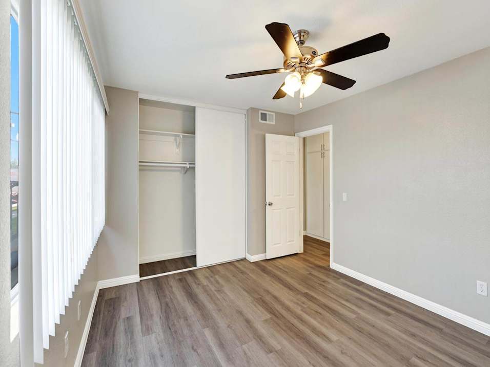 A room with a ceiling fan and wooden flooring.