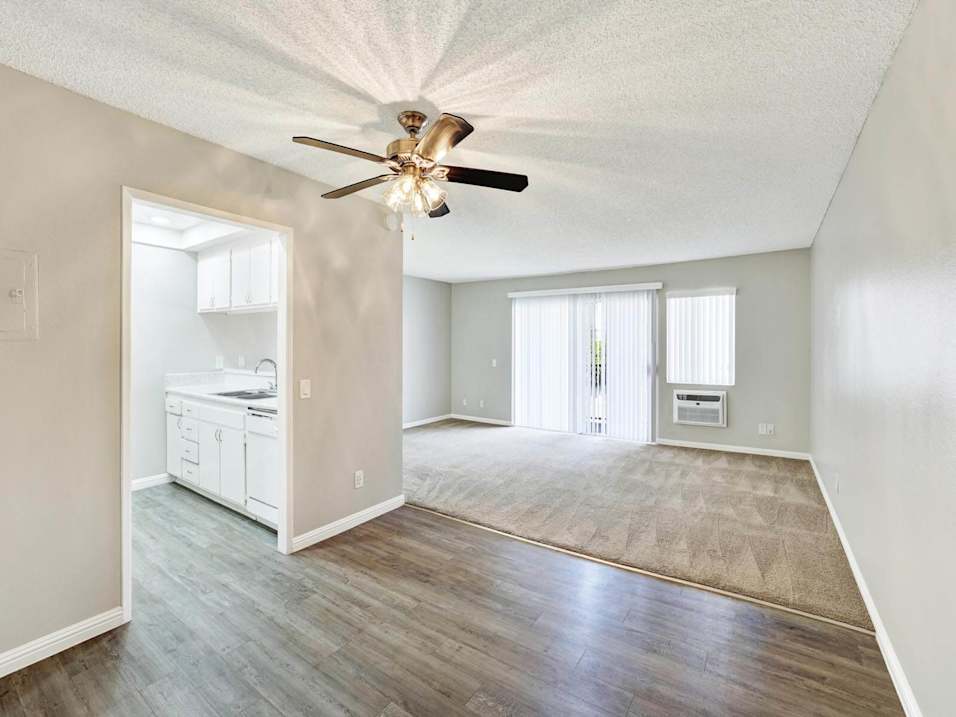 A room with a ceiling fan and wooden flooring.