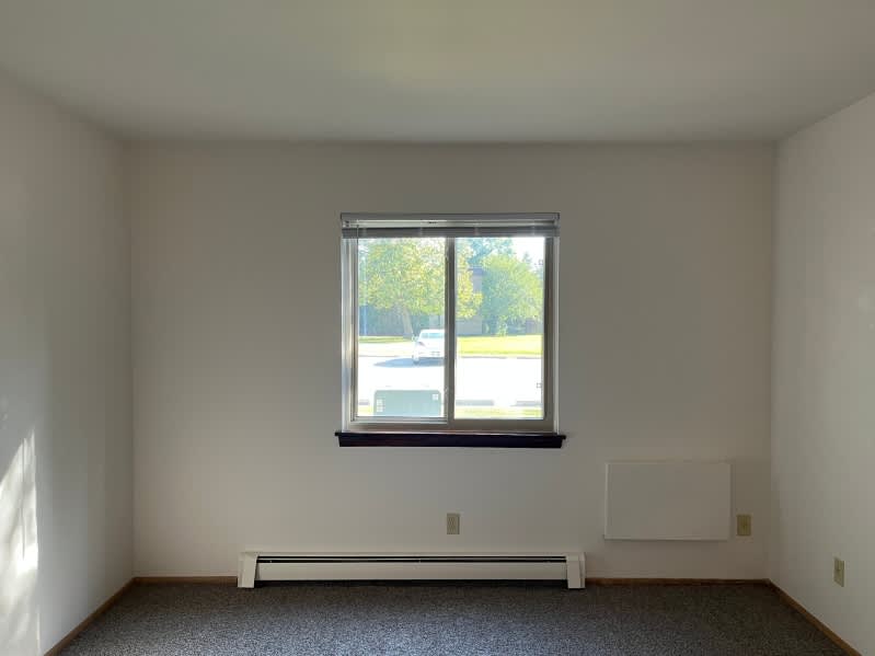 A room with a window and a radiator on the floor.