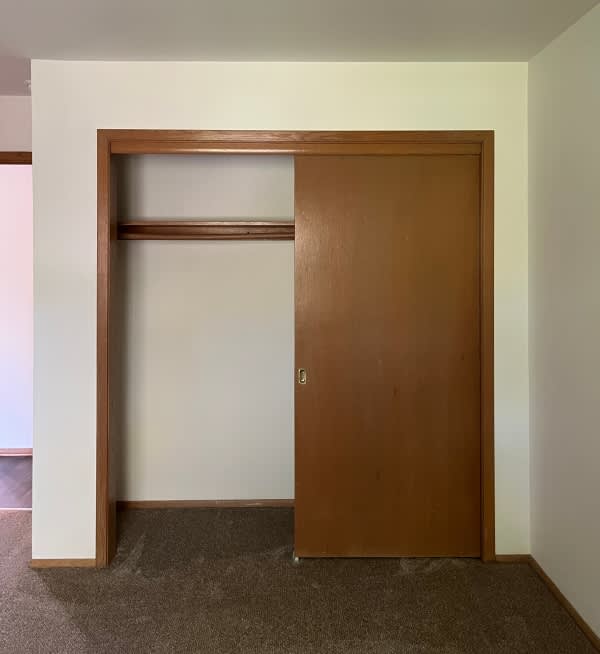 A brown door is in a white room.