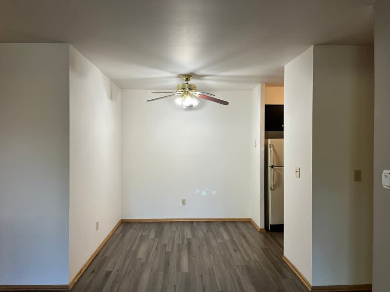 A room with a ceiling fan and wooden flooring.