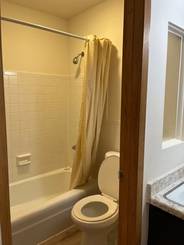 A white toilet in a bathroom with a shower curtain.