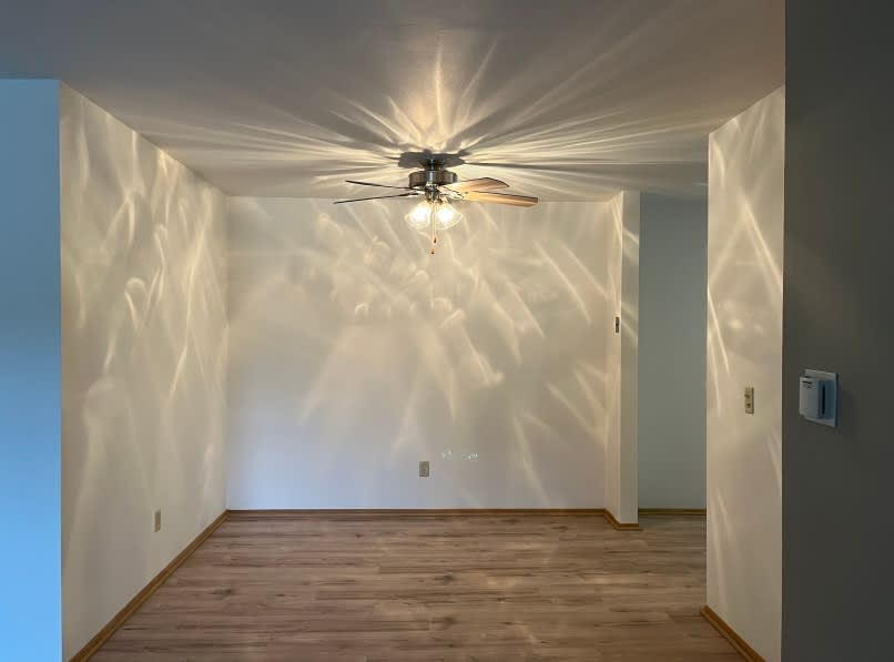 A room with a ceiling fan and wooden flooring.