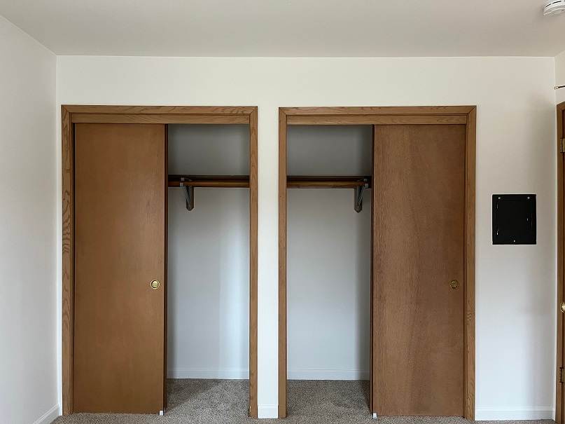 Two brown doors with windows in a white room.