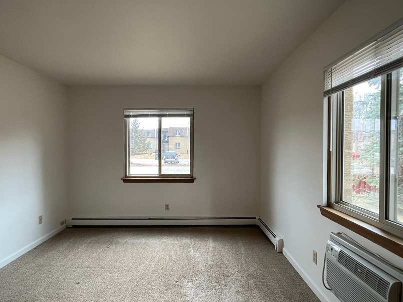 A room with a window and a carpeted floor.