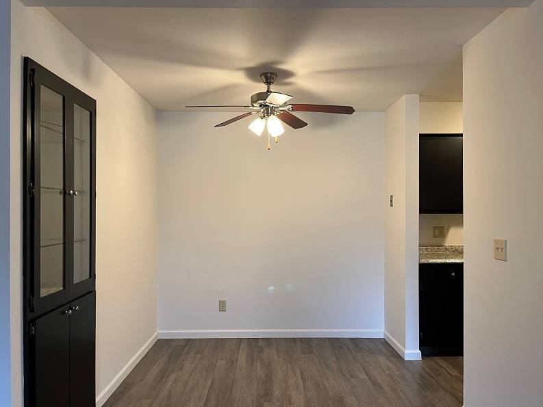 A room with a ceiling fan and a black door.