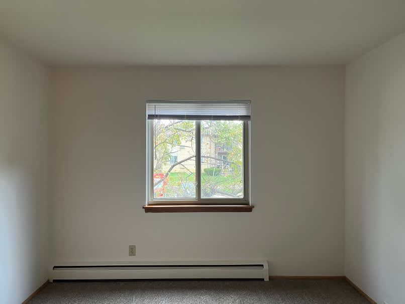 A room with a window and a white wall.