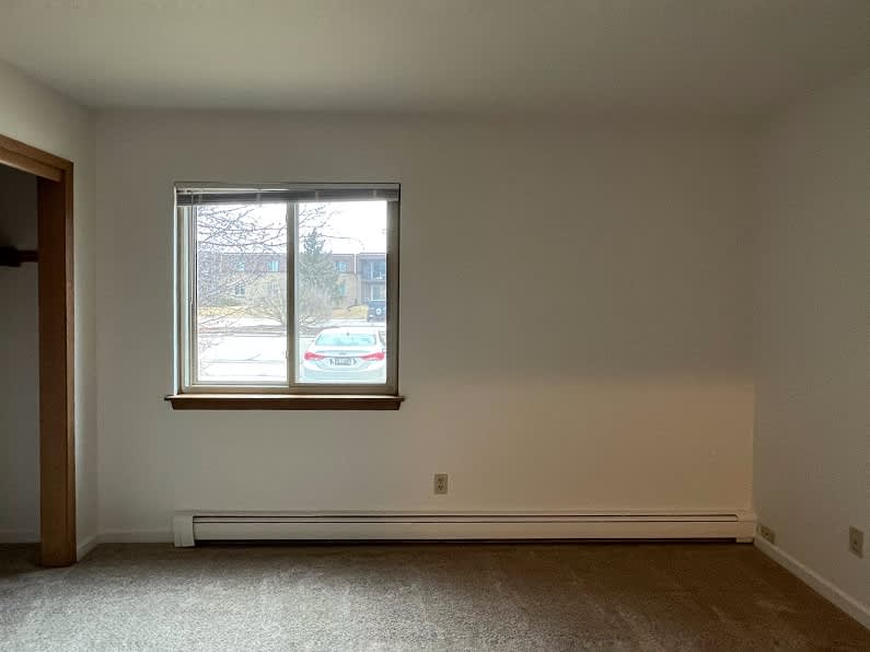 A room with a window and a white wall.