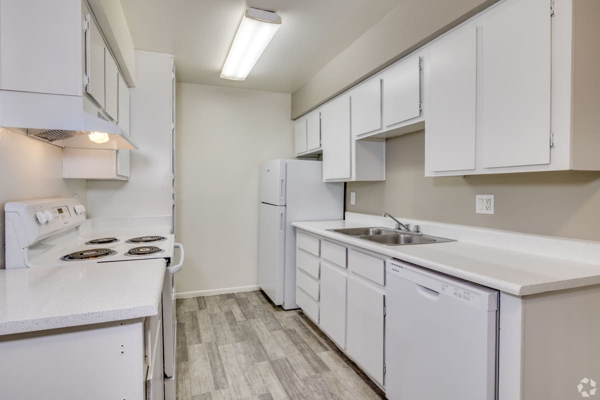 Galley kitchen with white cabinets and appliances at Sagewood Apartments