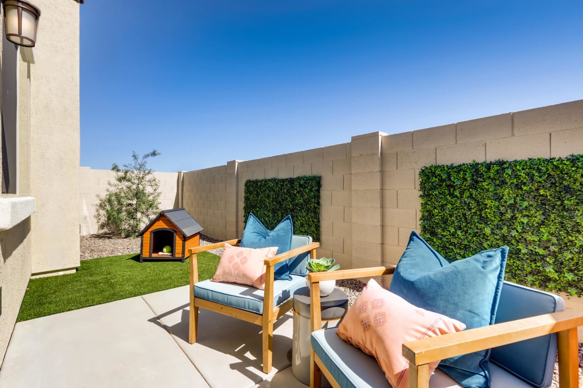 Model-home backyard with a fenced patio, seating and turf.
