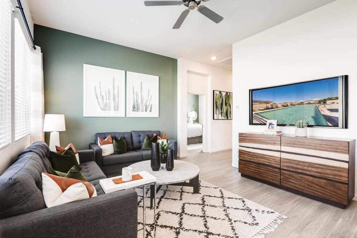 Model living room with a green accent wall and paired sofas.