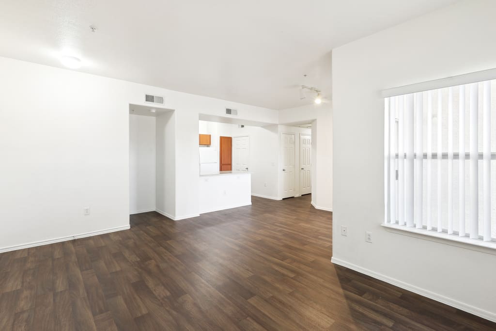 Unfurnished living room with a kitchen pass-through and wood-look flooring.