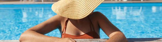 a woman in a sun hat laying by a swimming pool