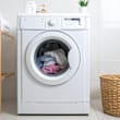 A white washing machine with the door open, containing a load of clothes.