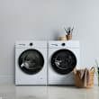Two white front loading washing machines in a room.