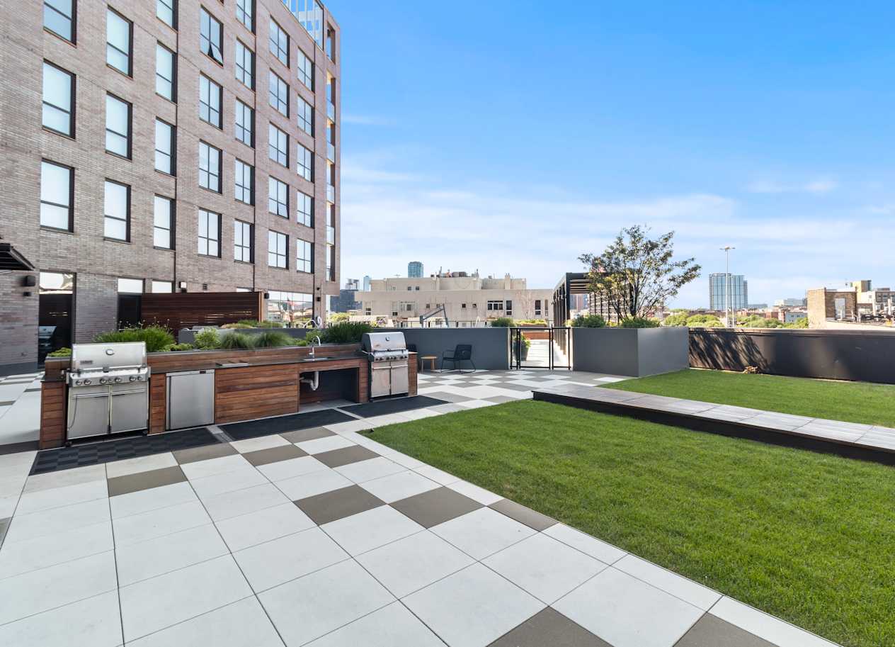 a rooftop patio with a lawn and a city skyline in the background