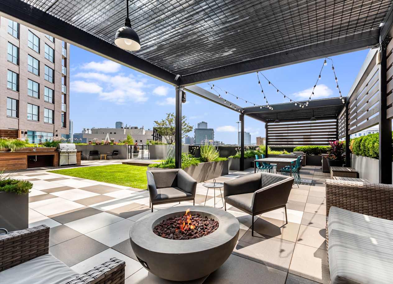 A patio with a fire pit and chairs.