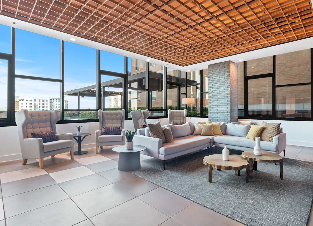 a living room with a couch and chairs in front of large windows