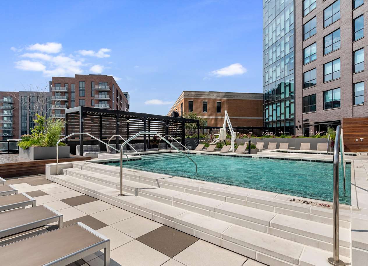 A pool surrounded by lounge chairs and a metal railing.