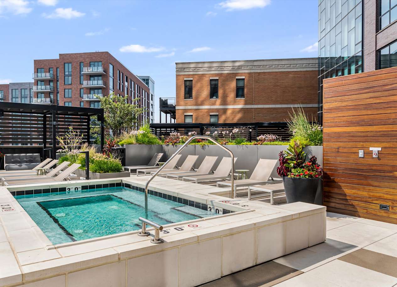 A pool surrounded by chairs and plants.