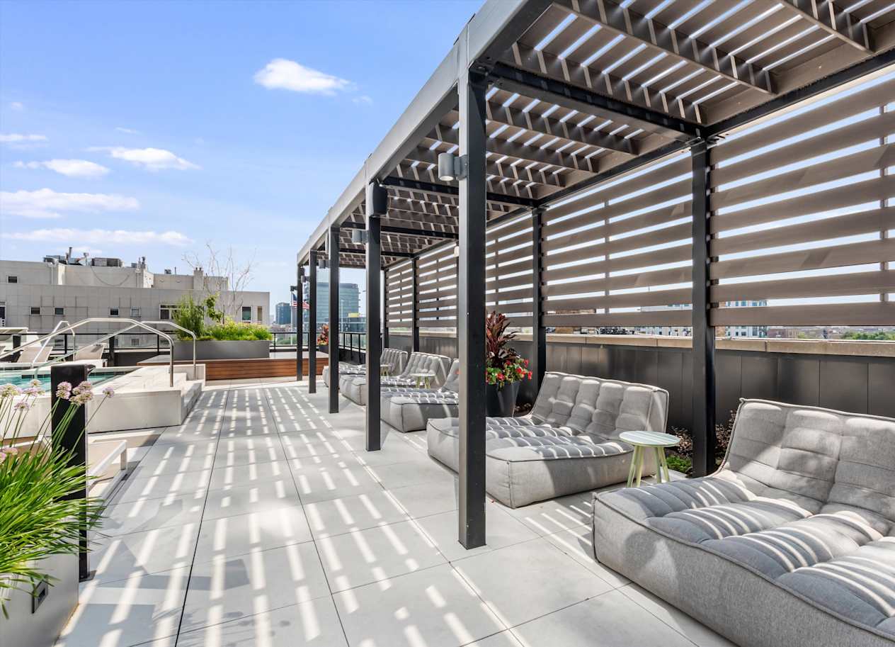 A patio with a grey couch and a table with a potted plant on it.