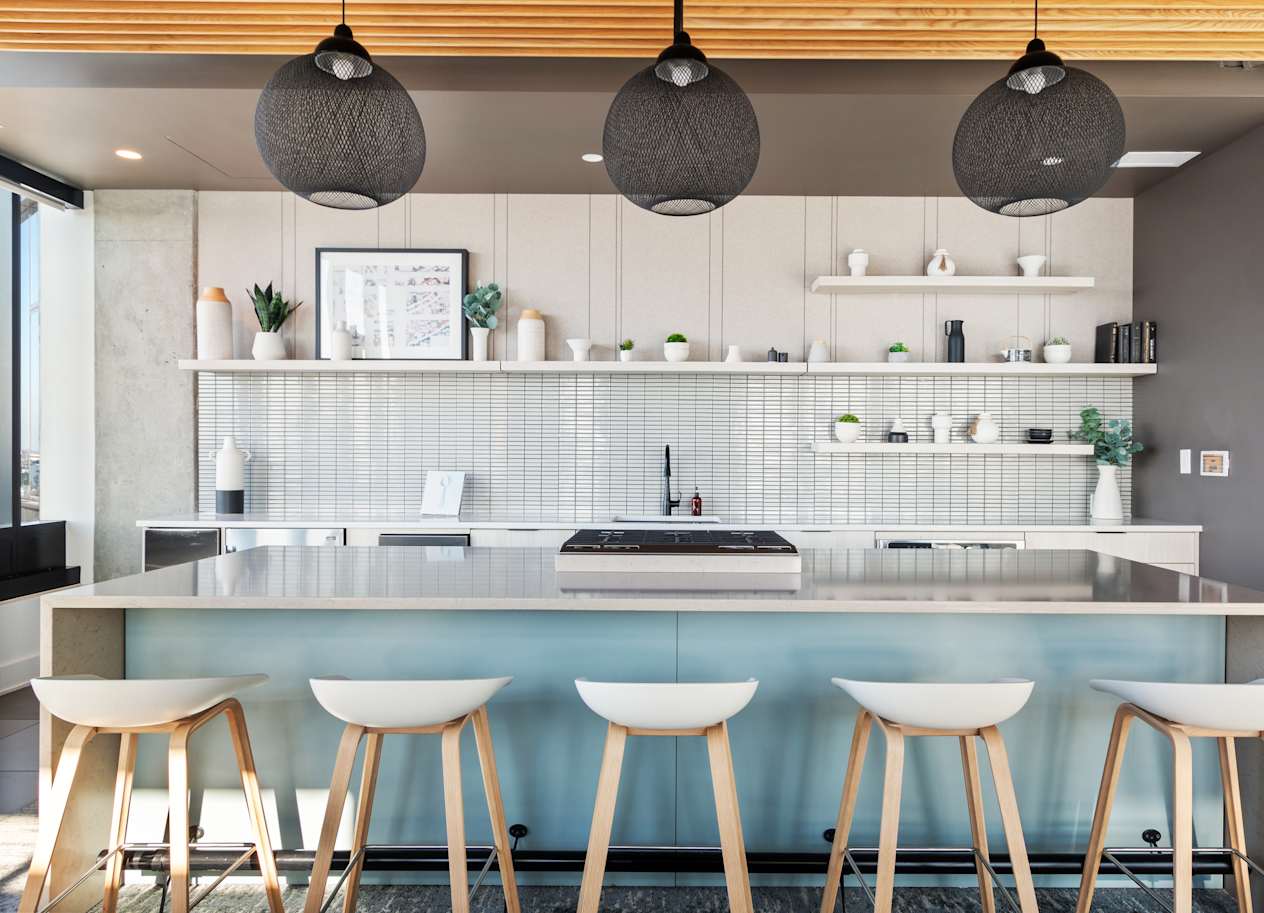 a kitchen with white stools in front of a counter top