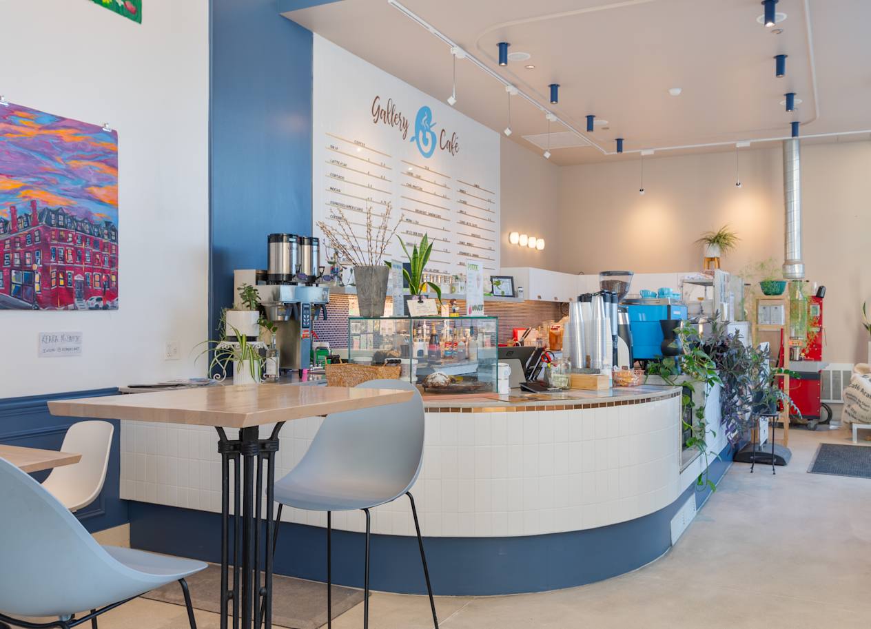 a cafe with a round table and chairs in front of a counter with coffee machines