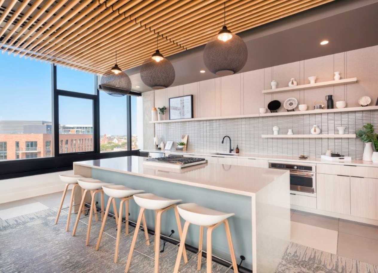 a kitchen with a long island and stools in front of a window