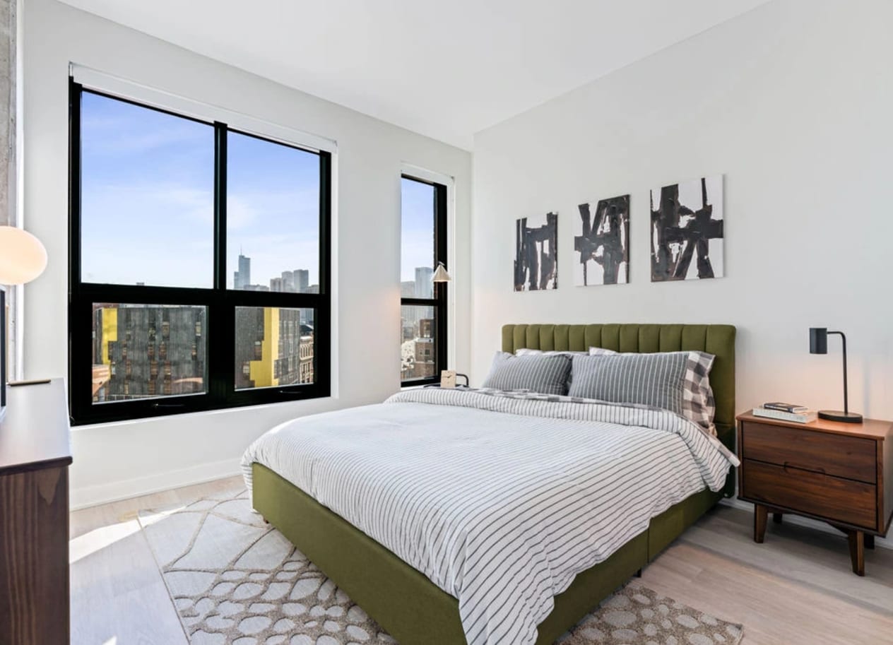 a bedroom with a large window and a bed with a green headboard