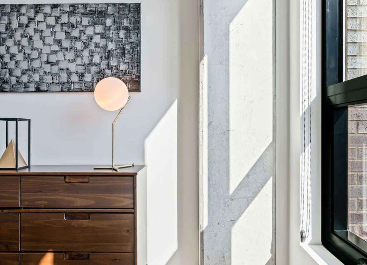 a bedroom with a bed and a dresser with a lamp on top of it