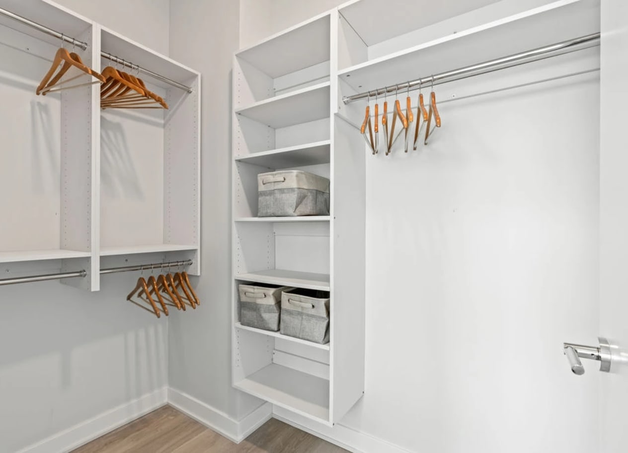 a walk in closet with white shelves and a white closet door