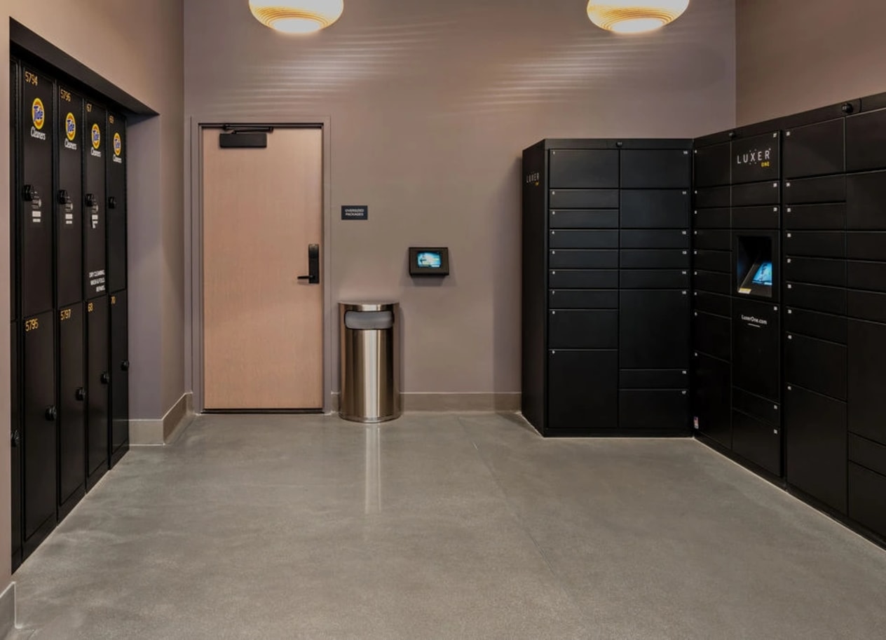 a row of black lockers in a room with a pink door