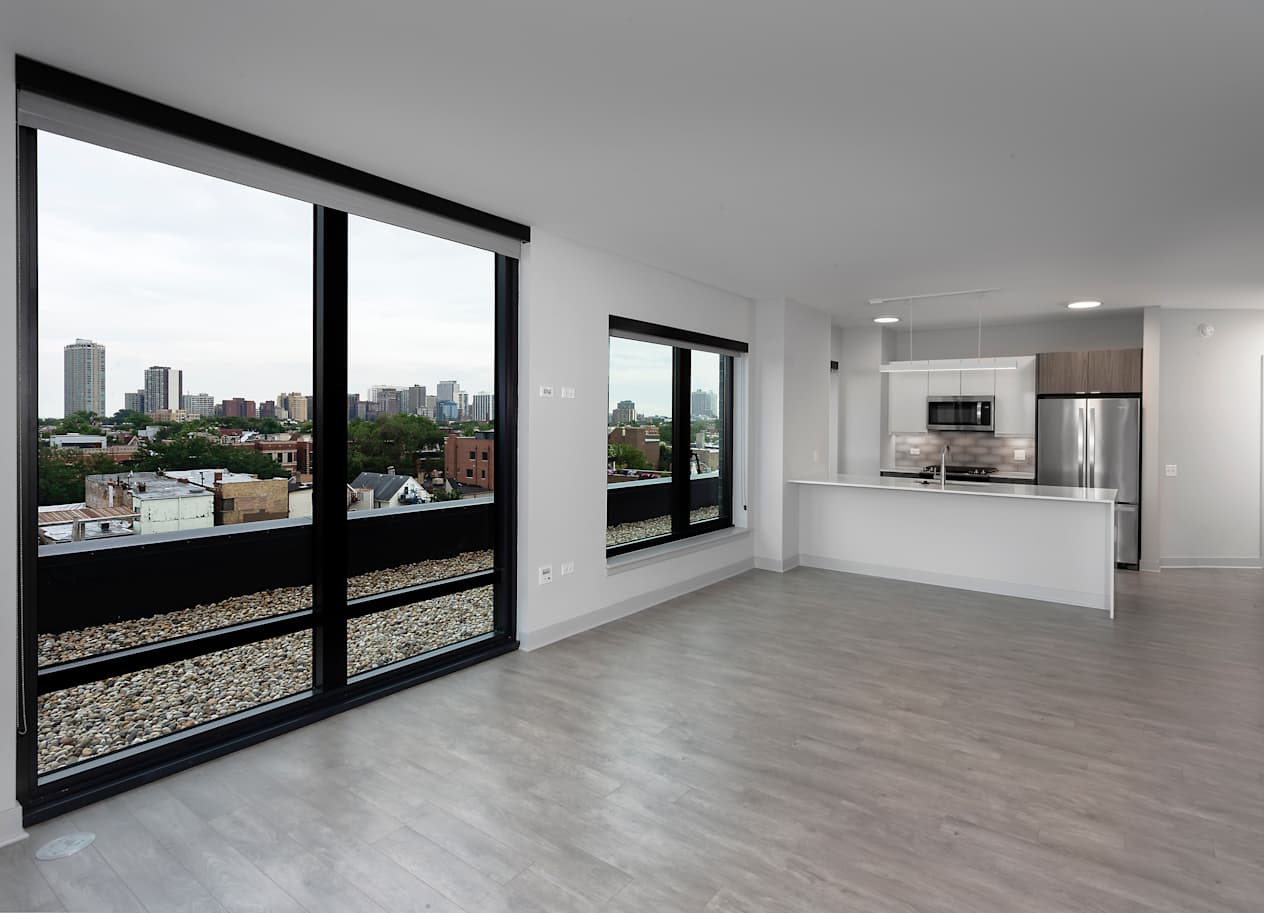 a living room and kitchen with large windows and a city view at Residences at Addison Clark Apartments, Chicago, 60613