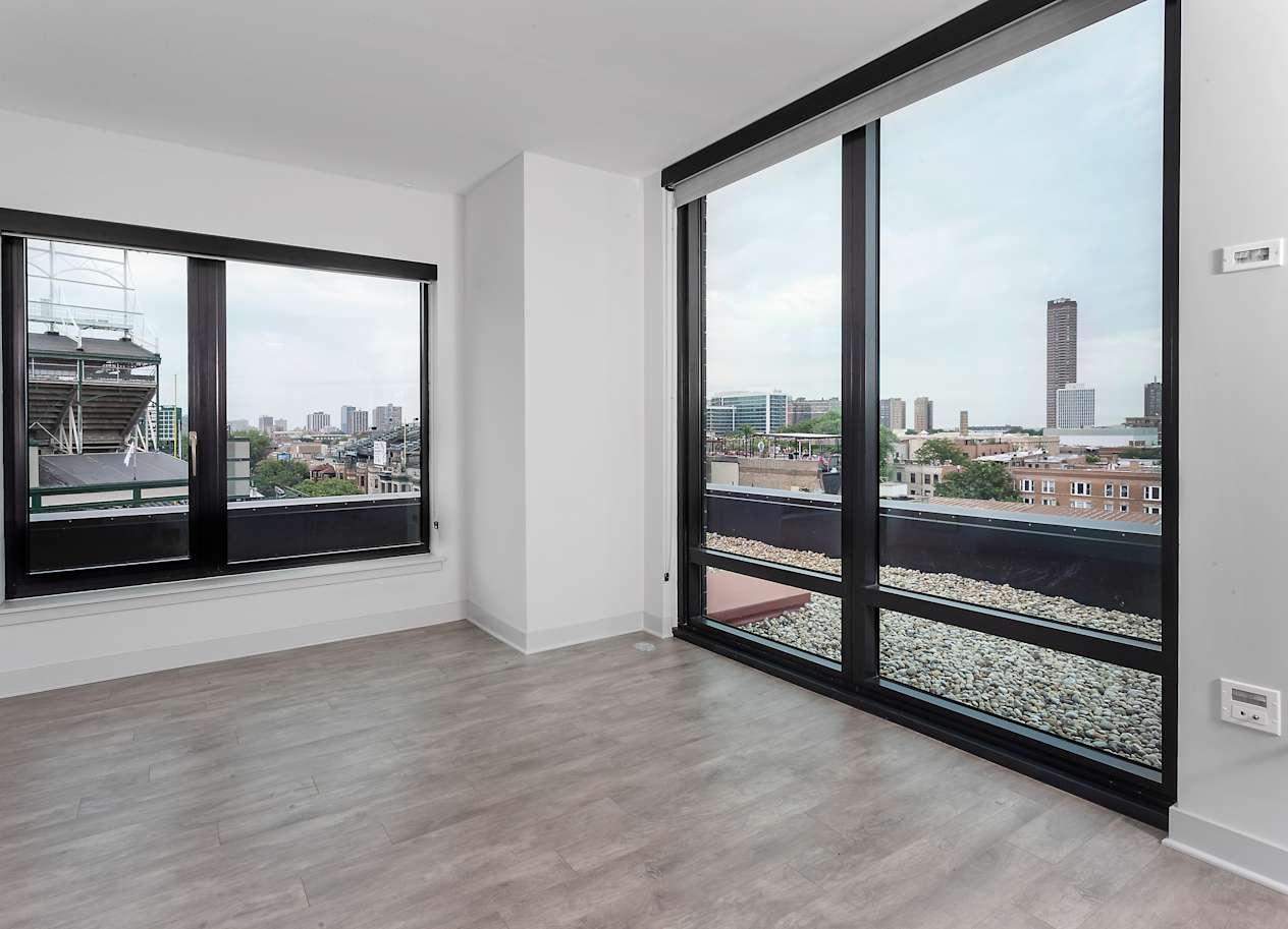a living room with large windows and a view of the city at Residences at Addison Clark Apartments, Chicago, 60613