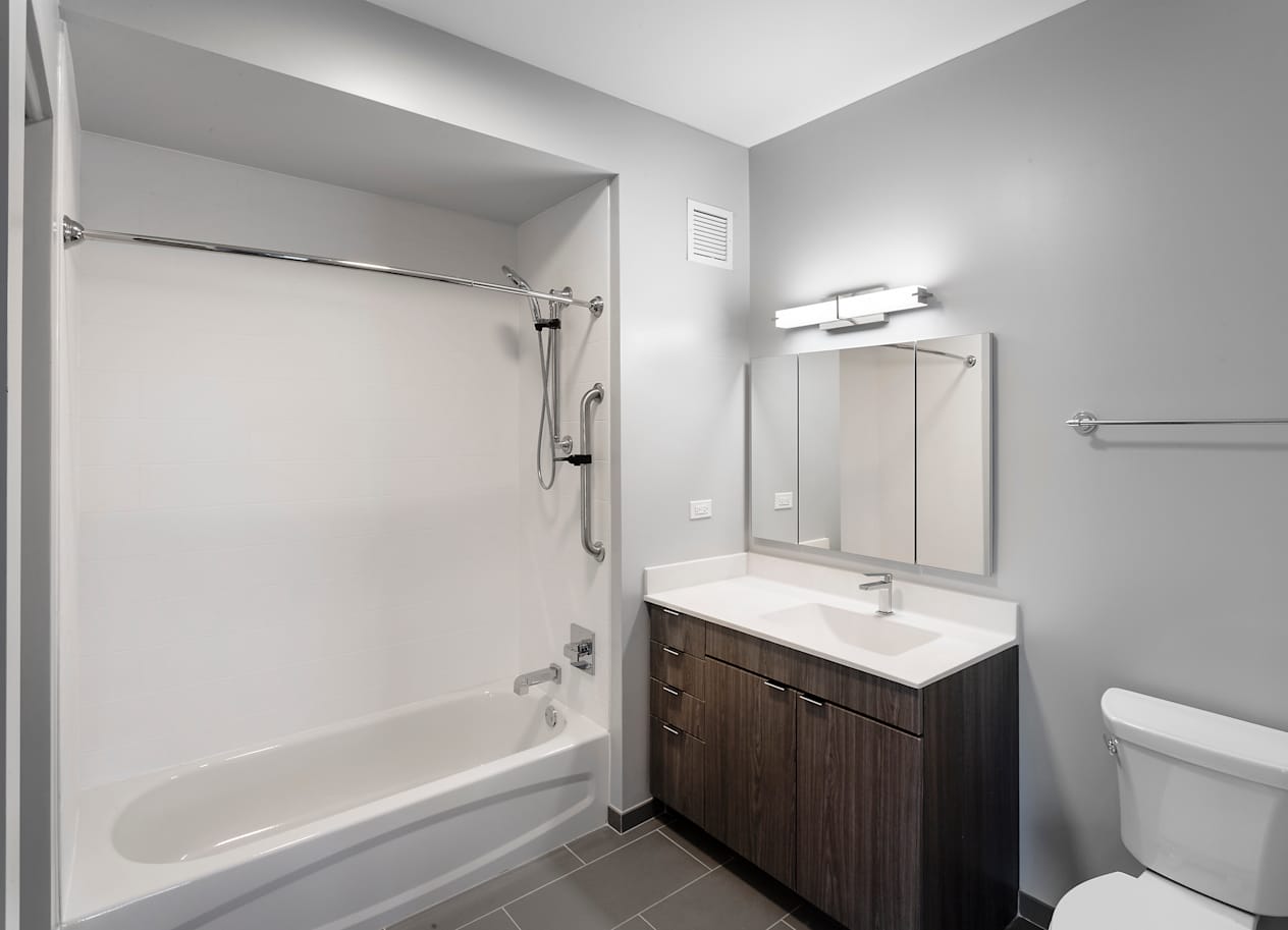 a bathroom with a toilet sink and shower and a mirror at Residences at Addison Clark Apartments, Chicago, IL