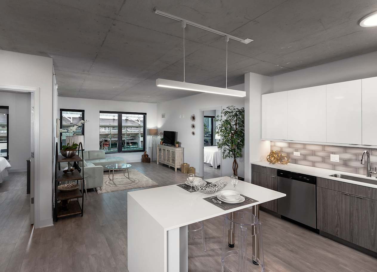 a kitchen and living room with a white island in the middle at Residences at Addison Clark Apartments, Chicago, 60613