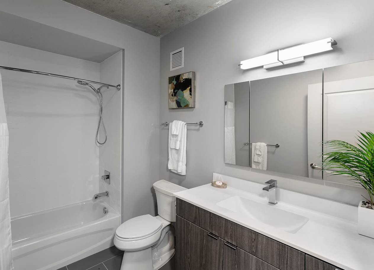 a bathroom with a shower toilet and sink and a mirror at Residences at Addison Clark Apartments, Chicago, IL, 60613