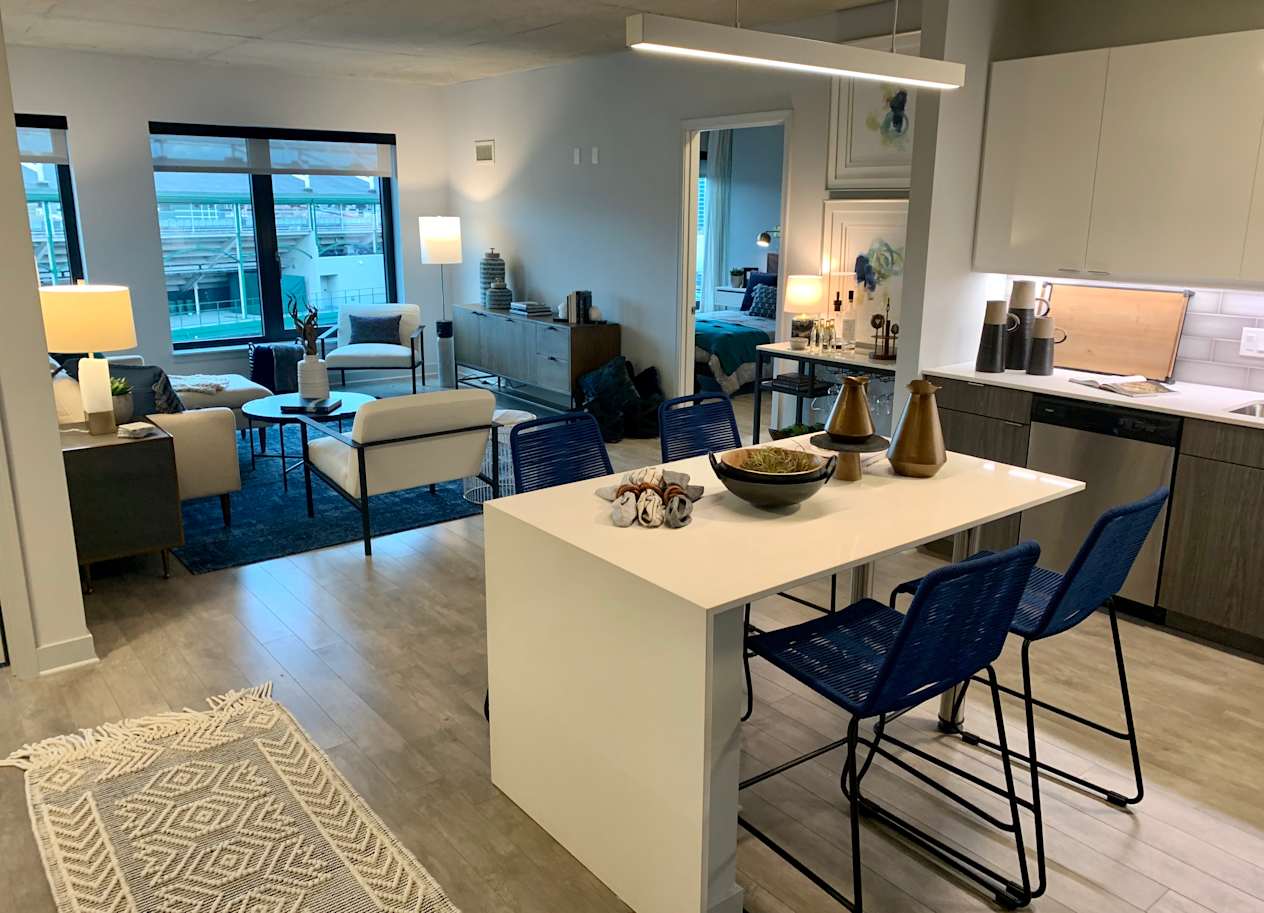 a kitchen and living room with a white island and blue chairs  at Residences at Addison Clark Apartments, Chicago