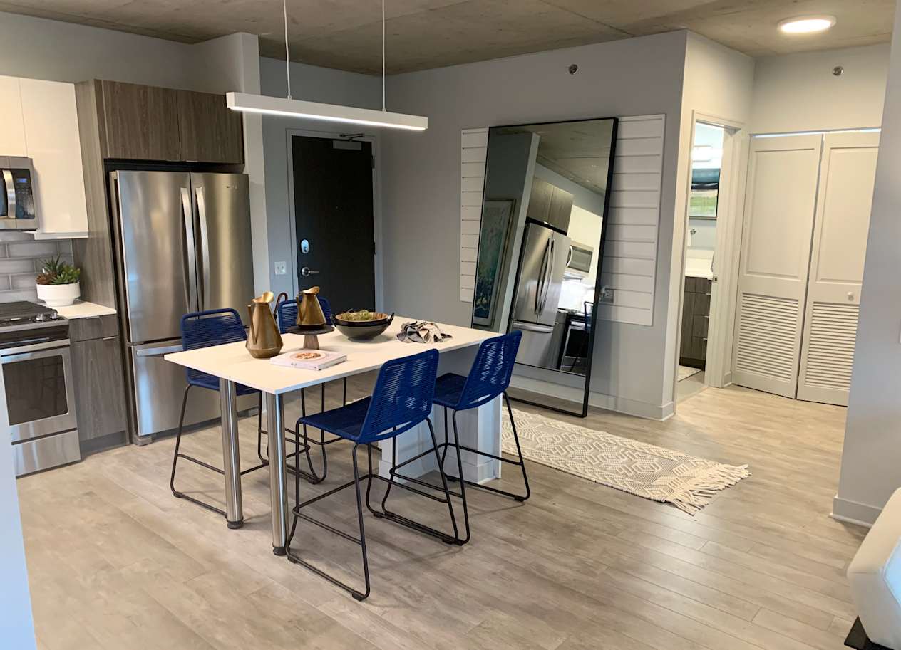 a kitchen and dining room with stainless steel appliances and a table with blue chairs  at Residences at Addison Clark Apartments, Chicago, IL, 60613
