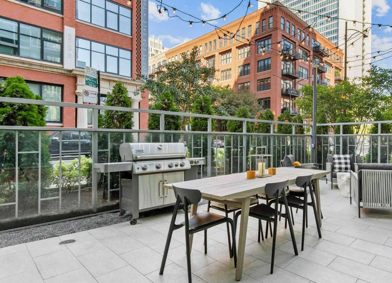 a patio with a table and chairs and a grill
