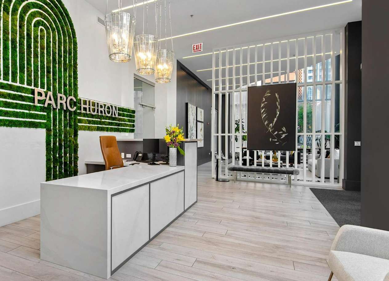 a reception area with a green logo on the wall and a white reception desk