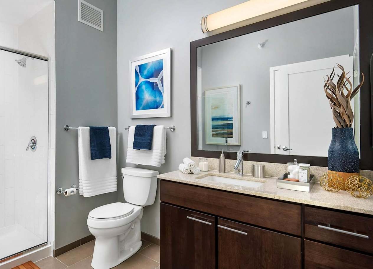 a bathroom with a toilet sink mirror and shower
