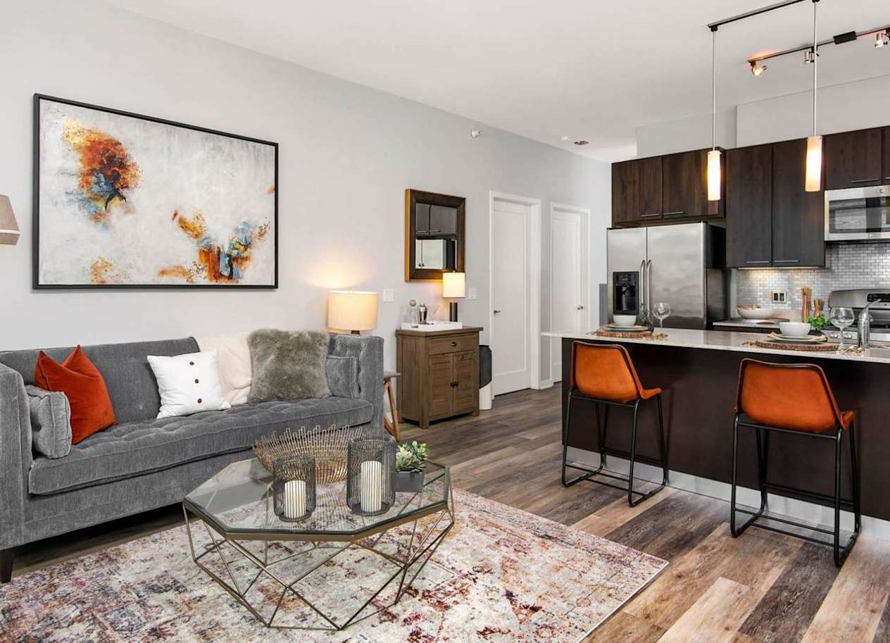 a living area with a couch coffee table and a kitchen in the background