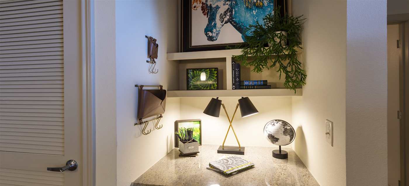 A desk set up as a work area with a lamp and a plant